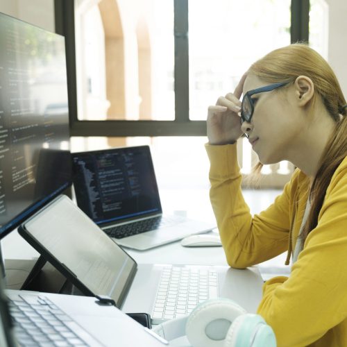 Young woman covering her face  with the stress of work coding and programming software. frustrated on her work and out of control.